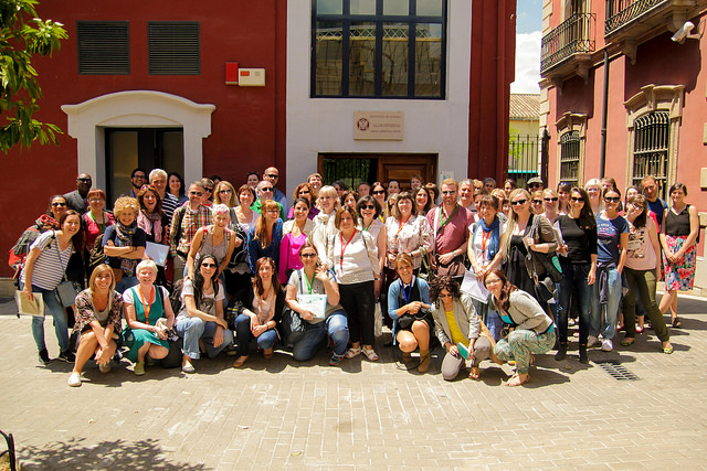 A large group of former participants posing for a photo outside the International Relations Office