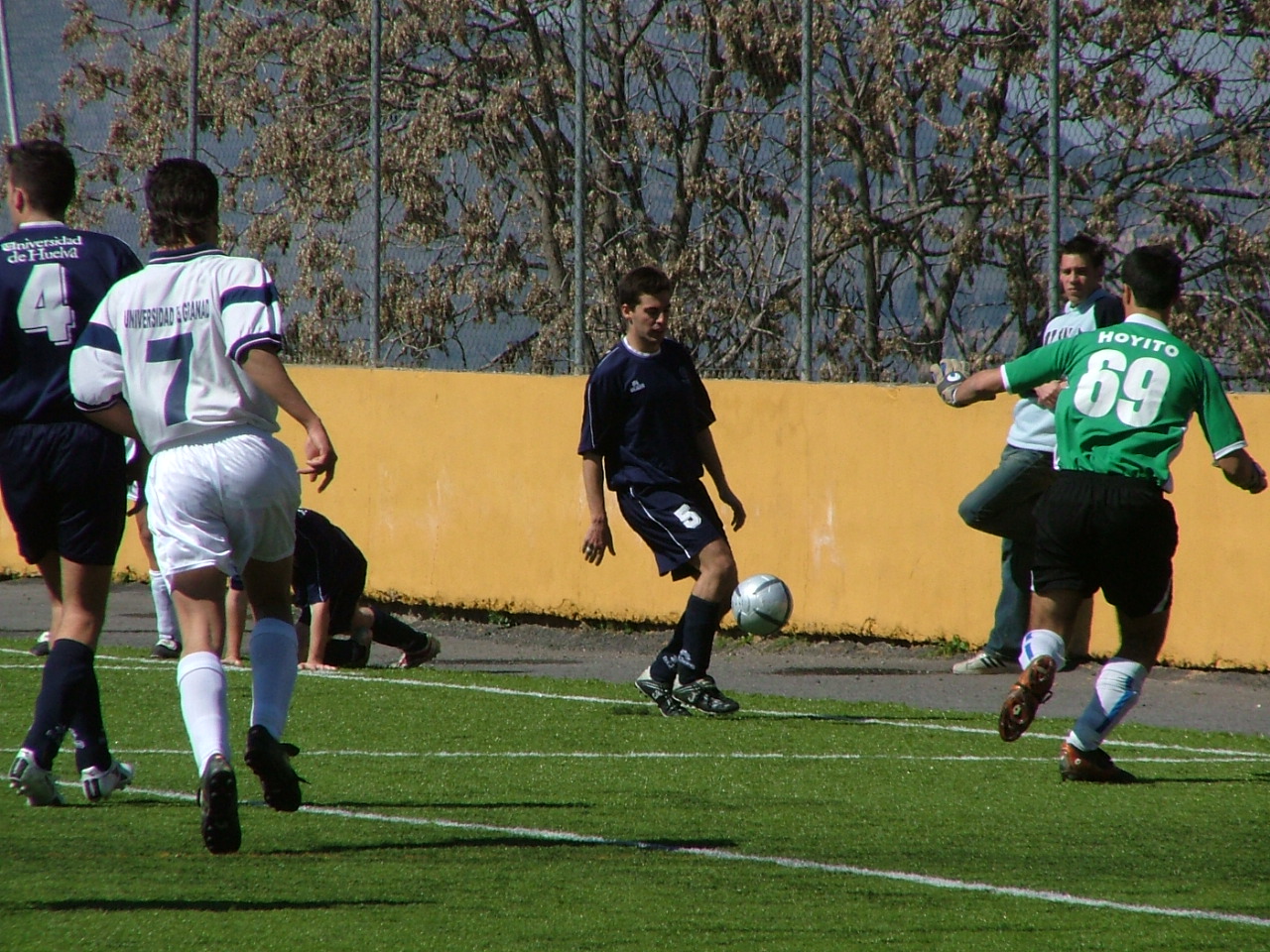 Varias personas jugando al fútbol sobre césped en el centro de actividades deportivas de la Universidad de Granada