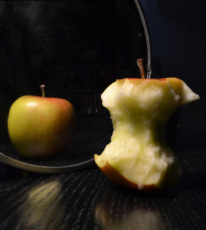 Visual trickery. An apple in the foreground is reflected merely as an apple core in a mirror in t...