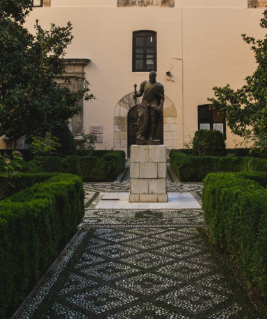 Patio con estatua en el centro y seto y árboles del Hospital Real