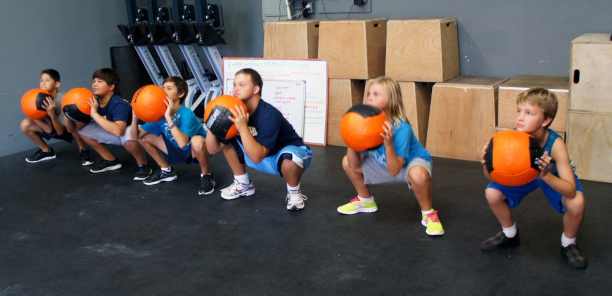 escolares entrenando la fuerza muscular con la ayuda de balones medicinales