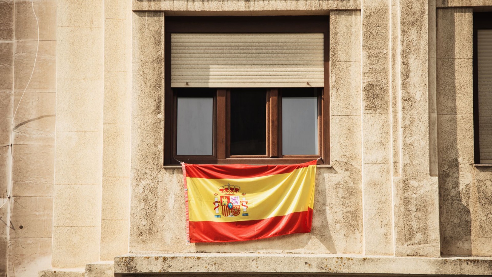 Bandera de España colgando de la fachada de un edificio