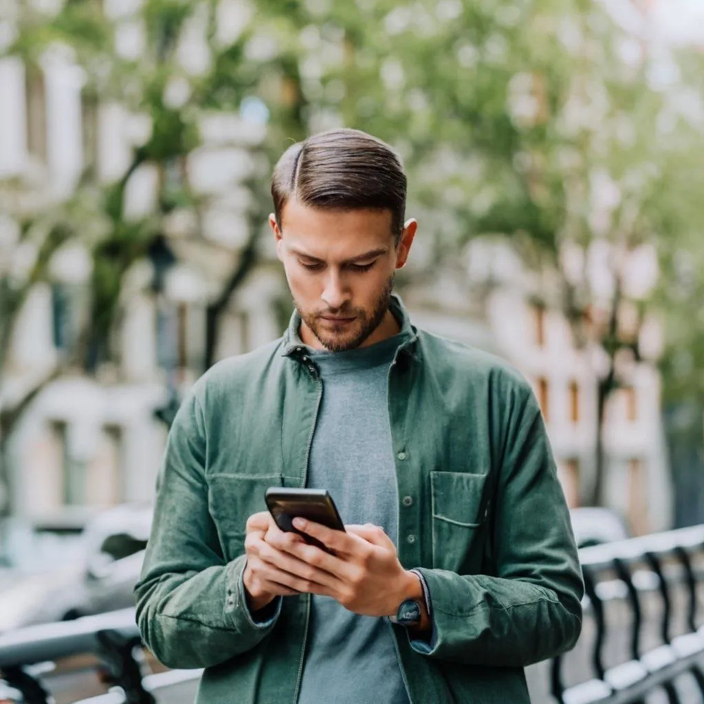 young man looking at his cell phone in the middle of the street