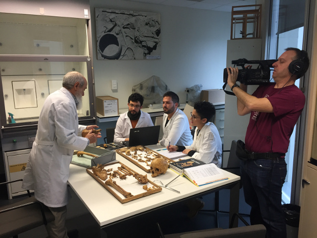 A university lecturer in a lab being recorded by a cameraman