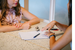 Two women sitting at a desk talking