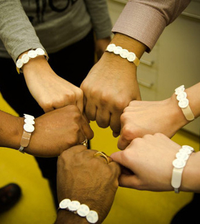 The arms of six people, of different skin tones, featuring the new wristband