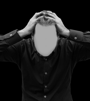 A man holding his head in desperation. His face is blurred out.
