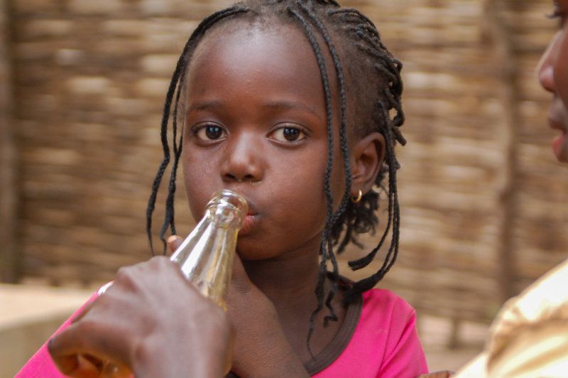 niña africana bebe de una botella de agua